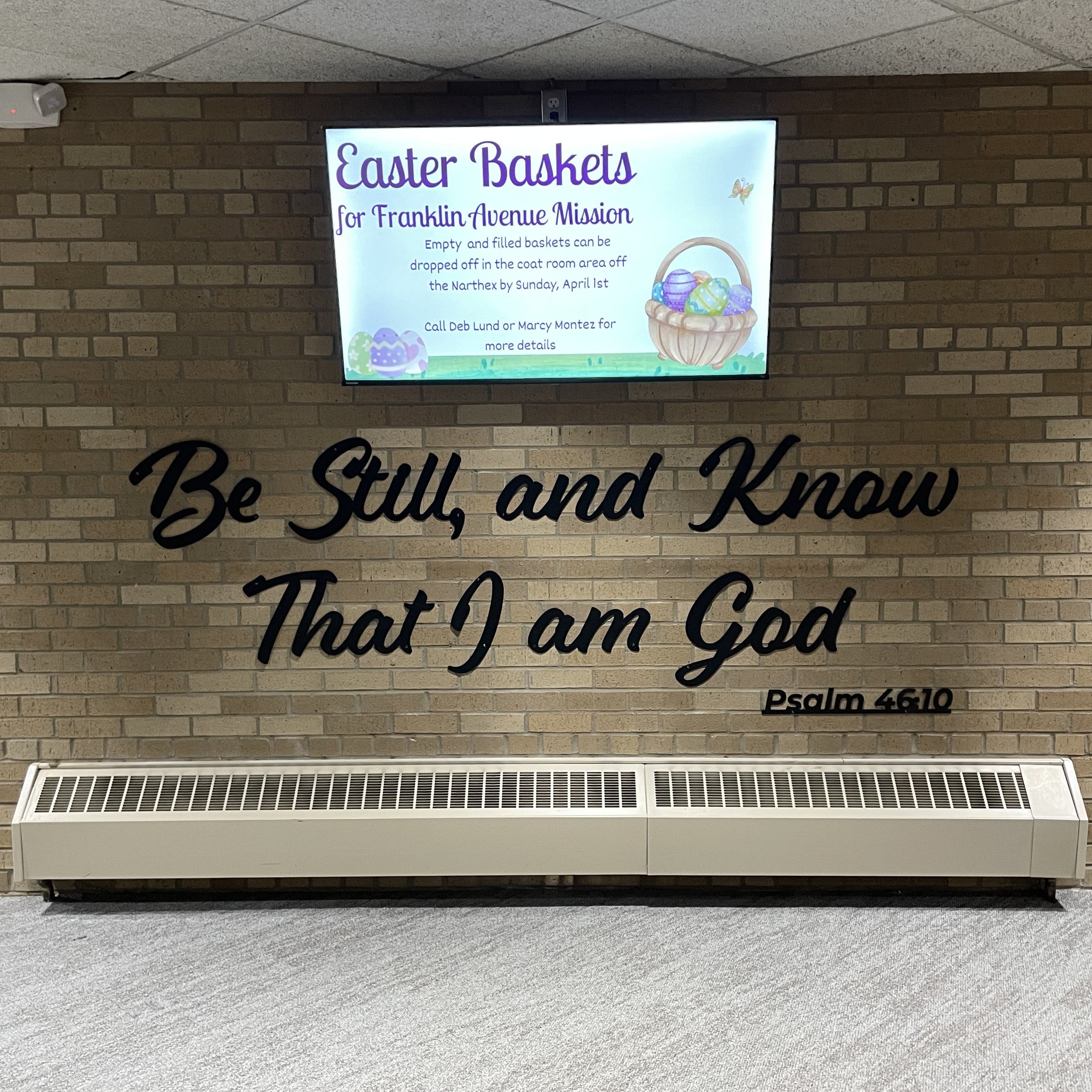 Wall with a television displaying an Easter message and a motivational quote with a Bible verse.